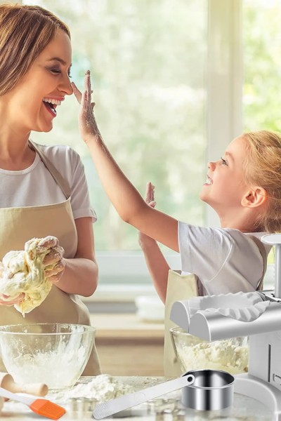 Matka z córką w kuchni podczas używania maszynki do lepienia pierogów