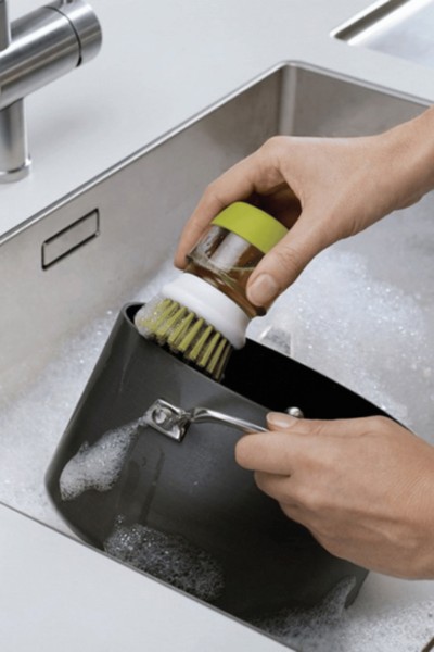 Mycie garnka szczotką z pojemnikiem na płyn do mycia naczyń